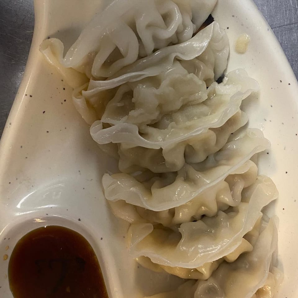A plate of Yama Fuji's steamed dumplings with a side of soy sauce.